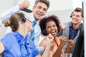 Cheerful customer service representatives and manager celebrating success in call center